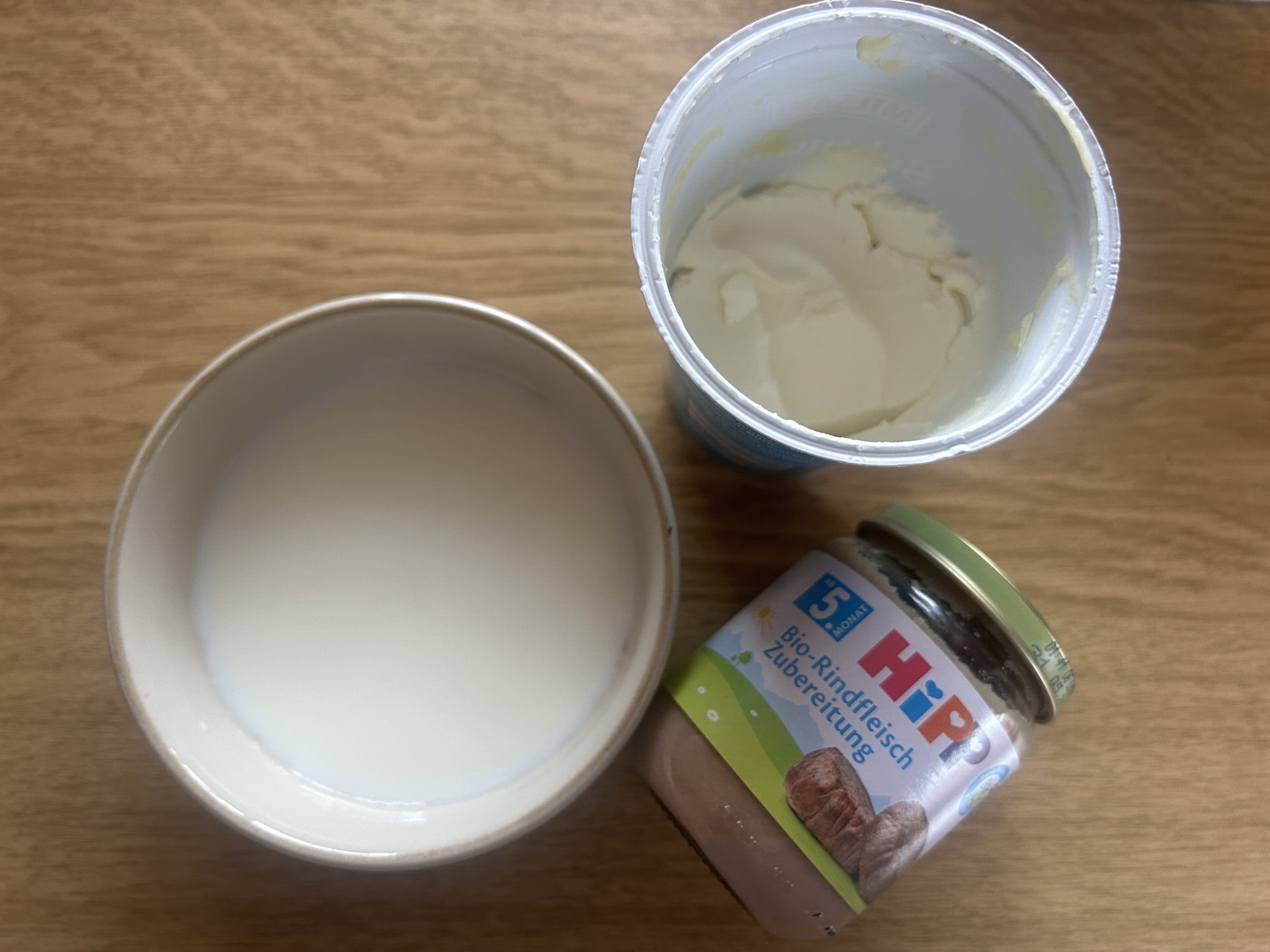 Schale mit milchiger Flüssigkeit,  Babygläschen mit Rind und Joghurt – Beispiele für schonende Küchenzutaten zum Päppeln von Katzen